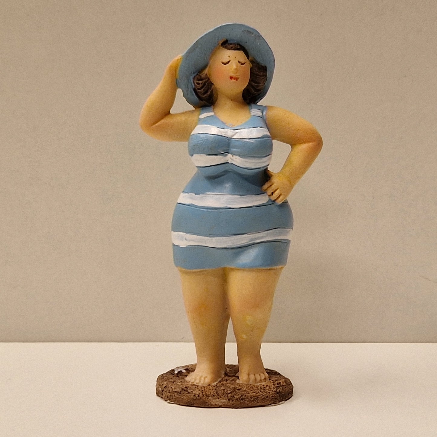 Lubben dame i stripete badedrakt og hatt, lys blå