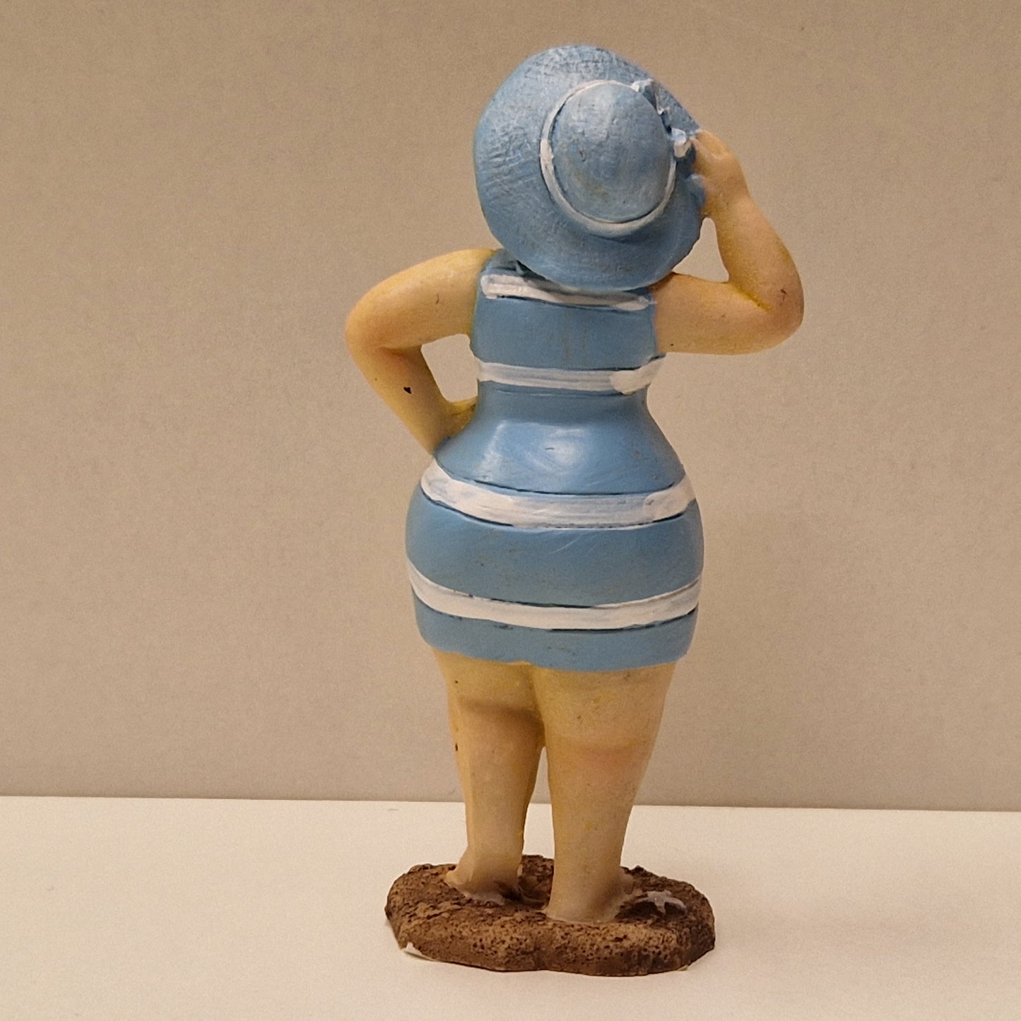 Lubben dame i stripete badedrakt og hatt, lys blå