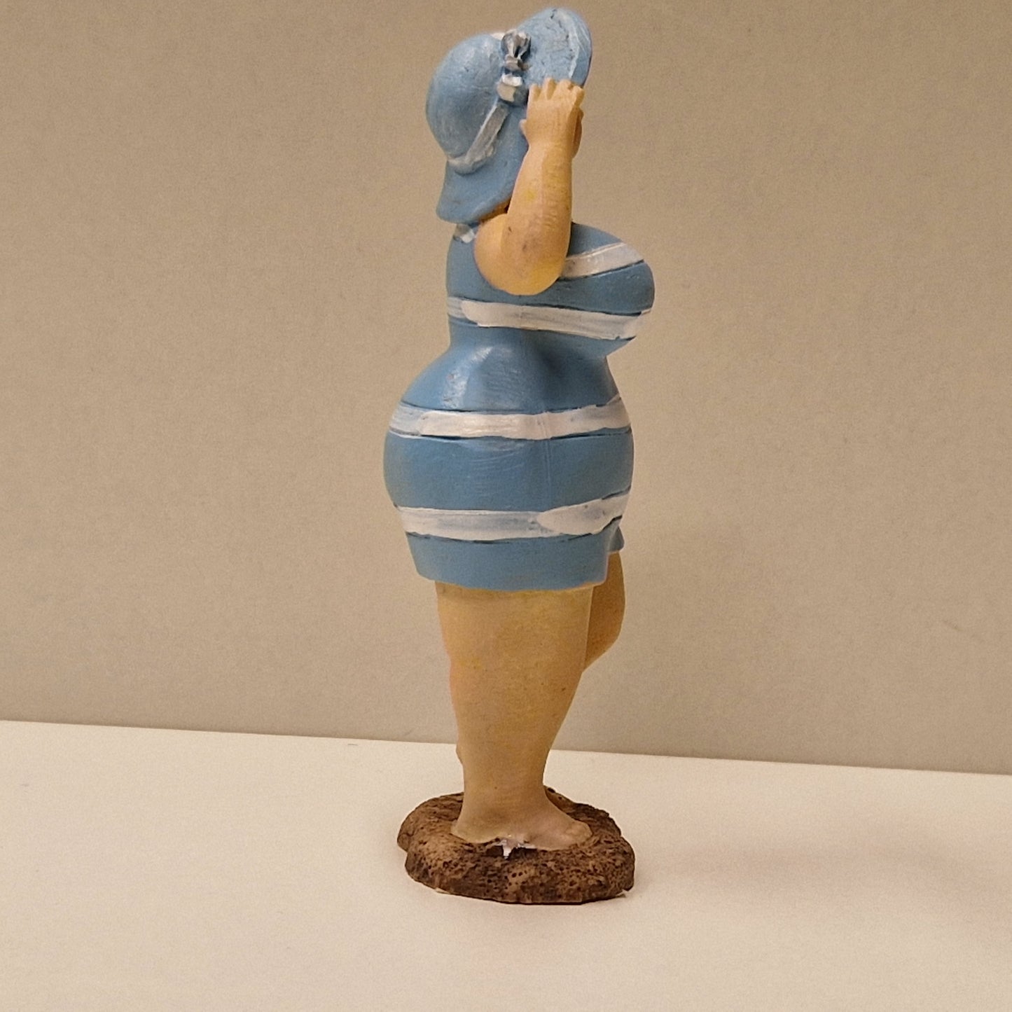 Lubben dame i stripete badedrakt og hatt, lys blå