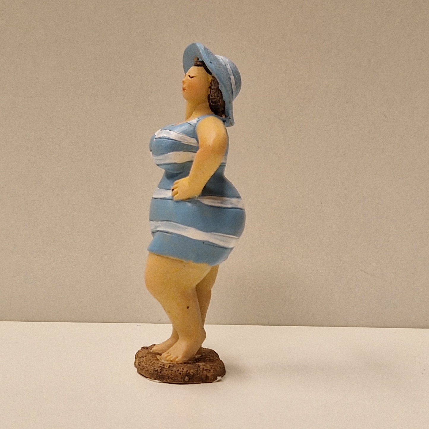 Lubben dame i stripete badedrakt og hatt, lys blå