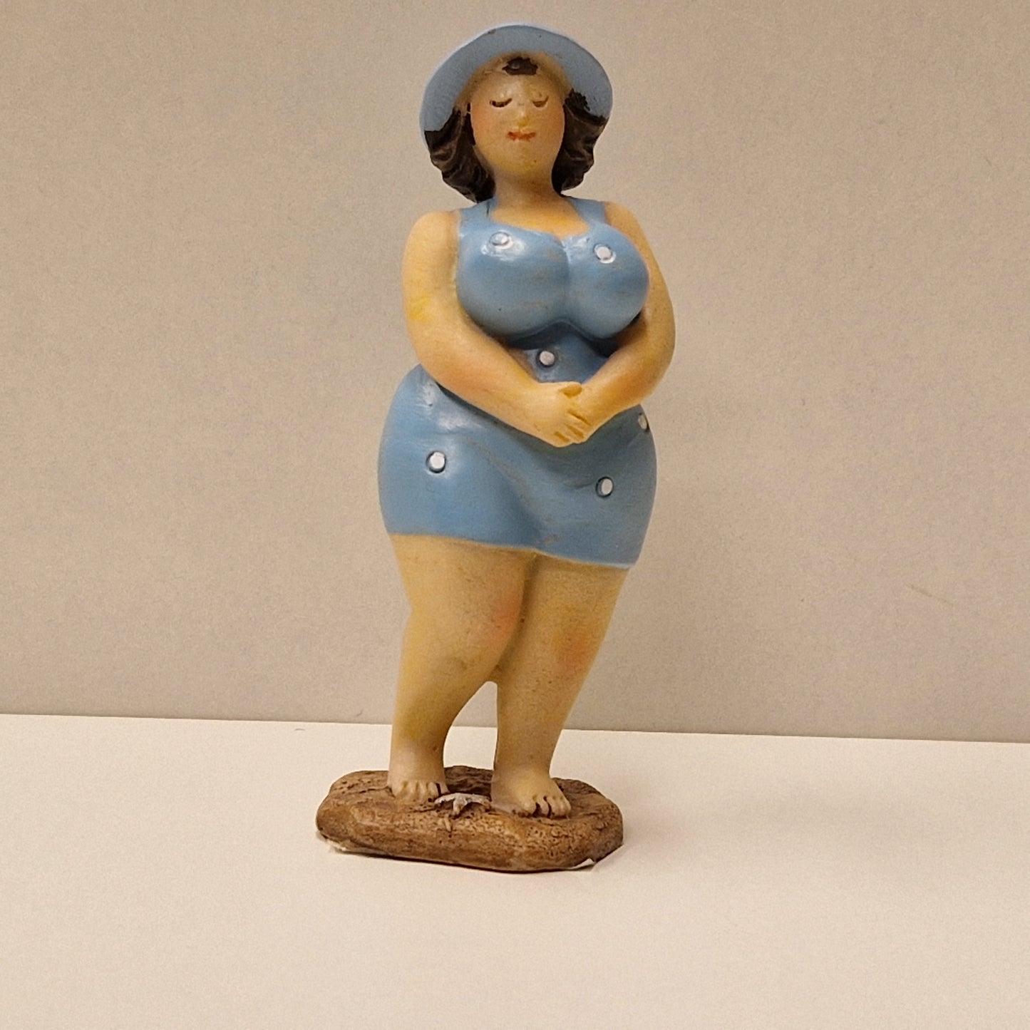 Lubben dame i prikkete badedrakt og hatt, lys blå