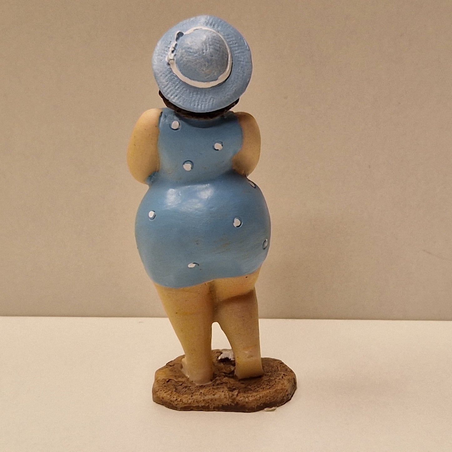 Lubben dame i prikkete badedrakt og hatt, lys blå