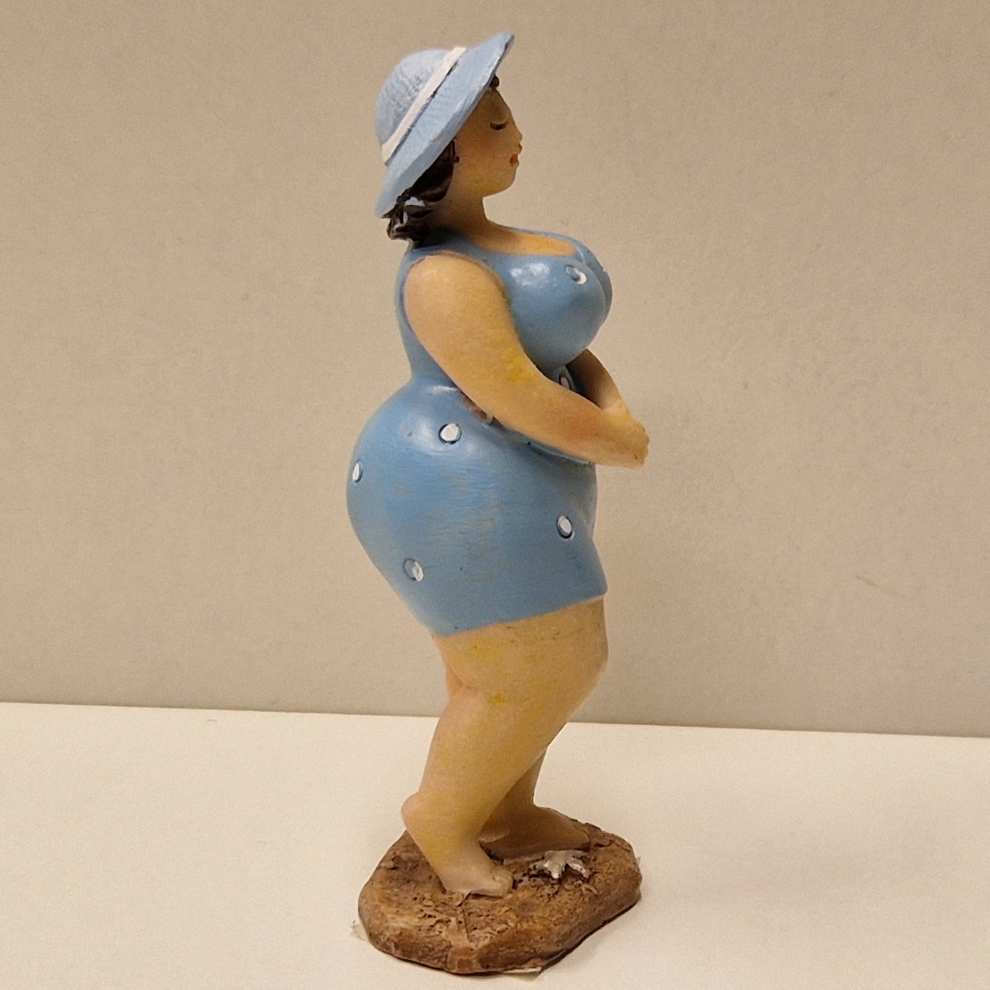 Lubben dame i prikkete badedrakt og hatt, lys blå