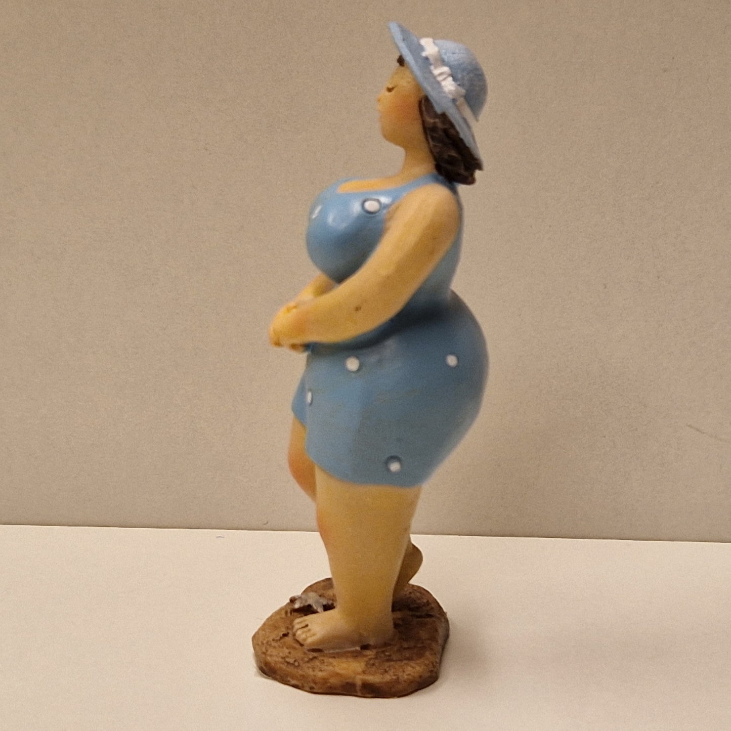 Lubben dame i prikkete badedrakt og hatt, lys blå