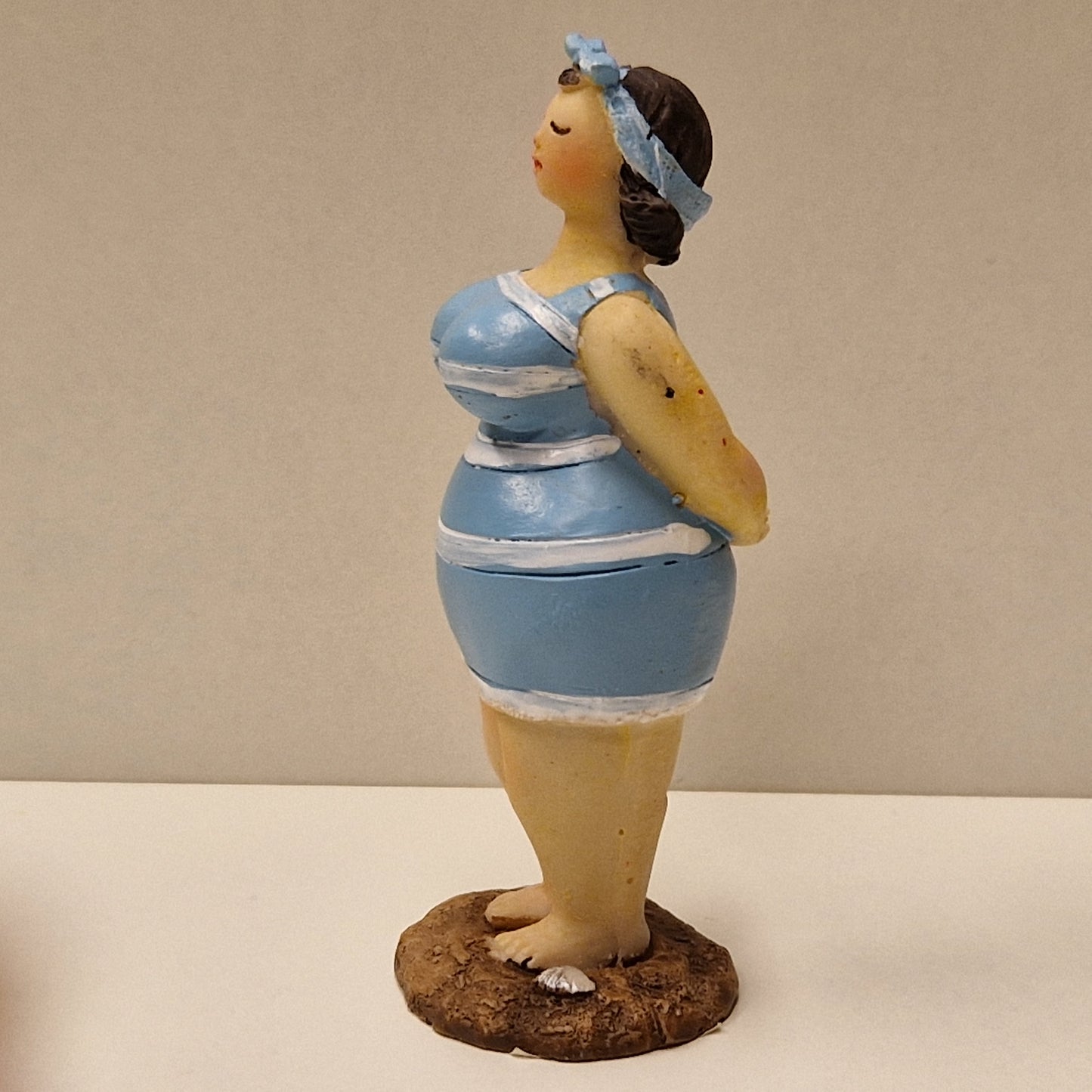 Lubben dame i stripete badedrakt og hårbånd, lys blå