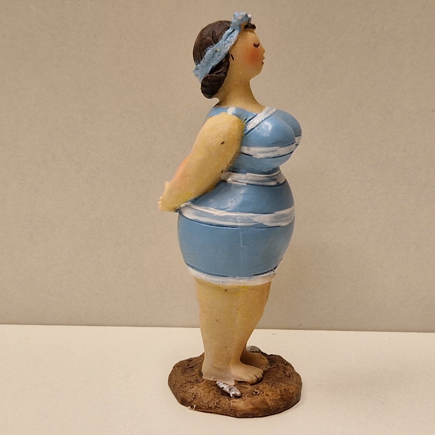 Lubben dame i stripete badedrakt og hårbånd, lys blå