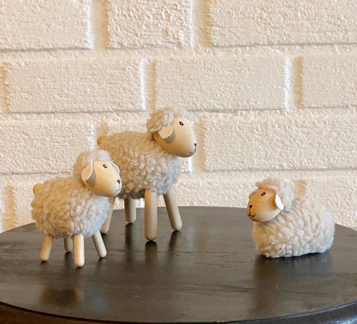 Sau av tre med beige ull, liggende